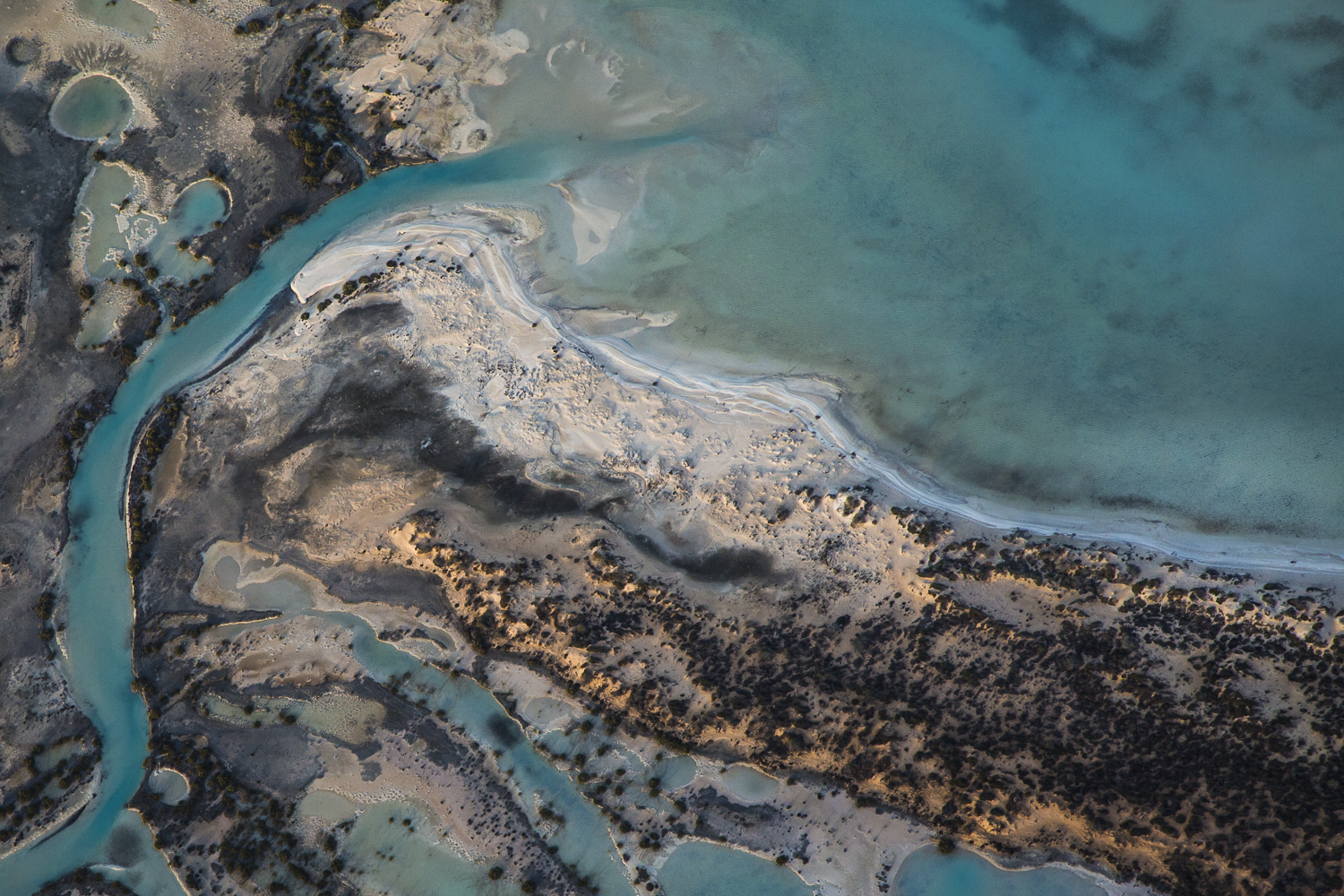 A horizontal abstract aerial photo of water taken in Australia in colour of blue, green and grey .