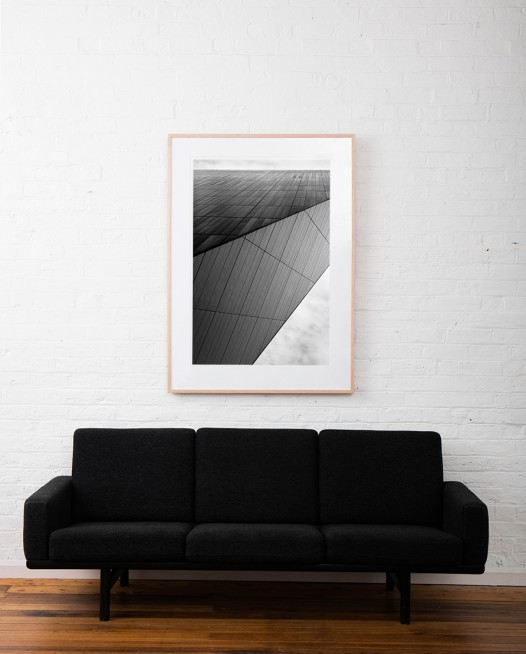 Large Vertical black and white photographic art print of buildings by Alan Moyle framed on raw timber above sofa