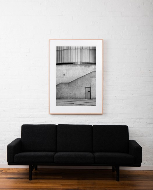 Large Vertical Black and white photographic art print of buildings and doorway by Allan Moyle framed in raw timber above sofa