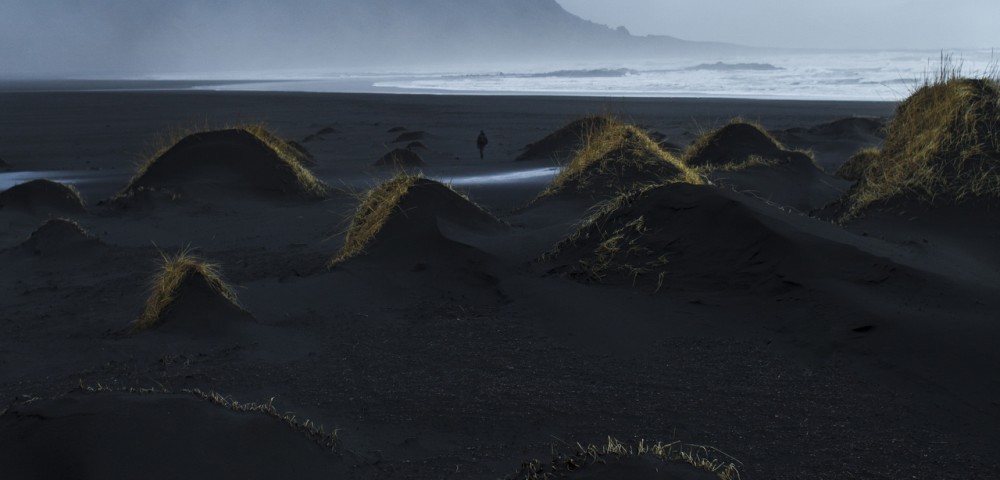 A misty photographic image of icelandic landscape of beaches, sea and mountains in shades of blue