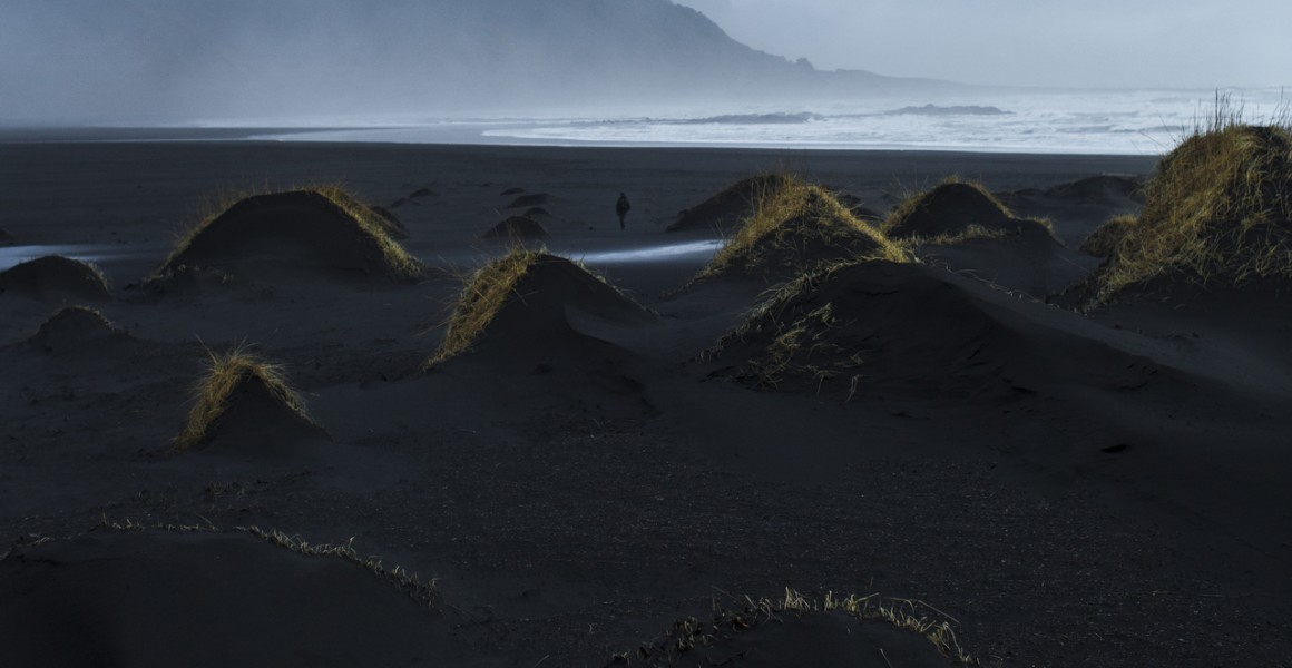 A misty photographic image of icelandic landscape of beaches, sea and mountains in shades of blue