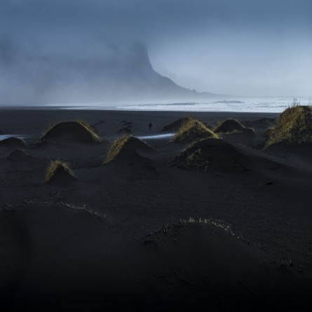 A misty photographic image of icelandic landscape of beaches, sea and mountains in shades of blue