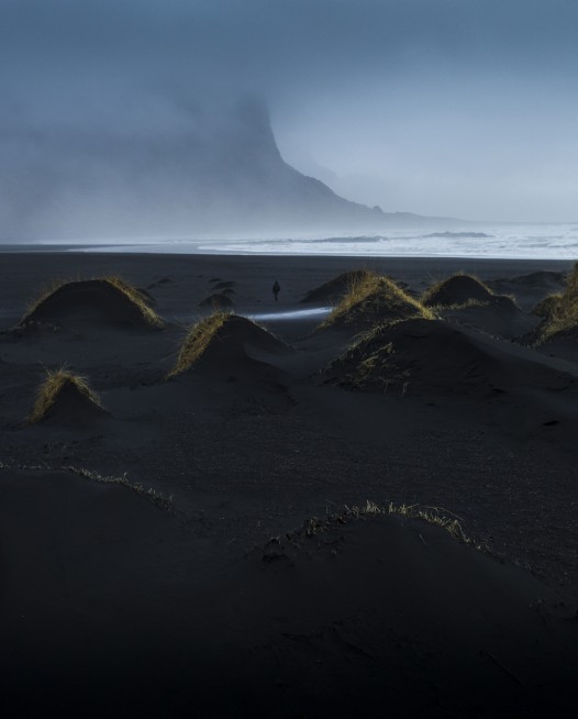 A misty photographic image of icelandic landscape of beaches, sea and mountains in shades of blue