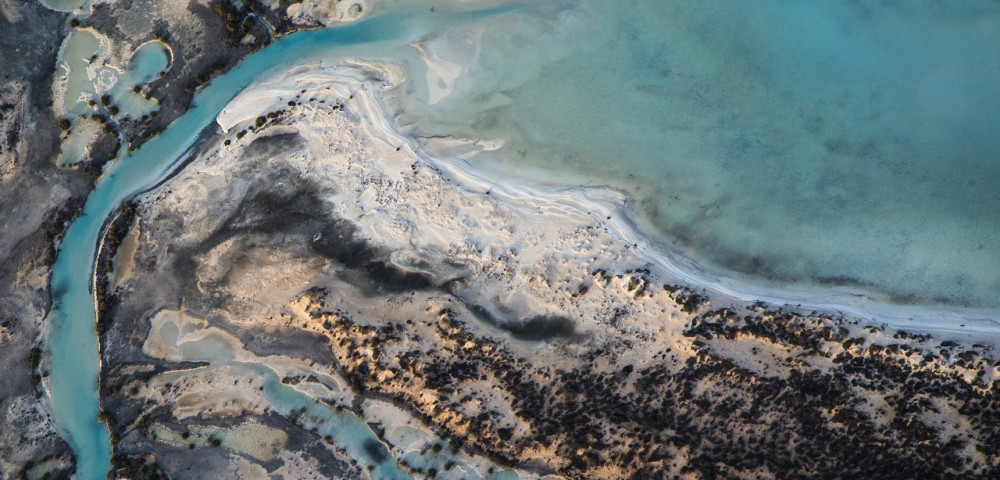 A horizontal abstract aerial photo of water taken in Australia in colour of blue, green and grey