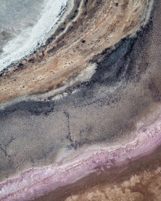 A horizontal abstract, aerial photo of Australia water in pink, purple, and red.