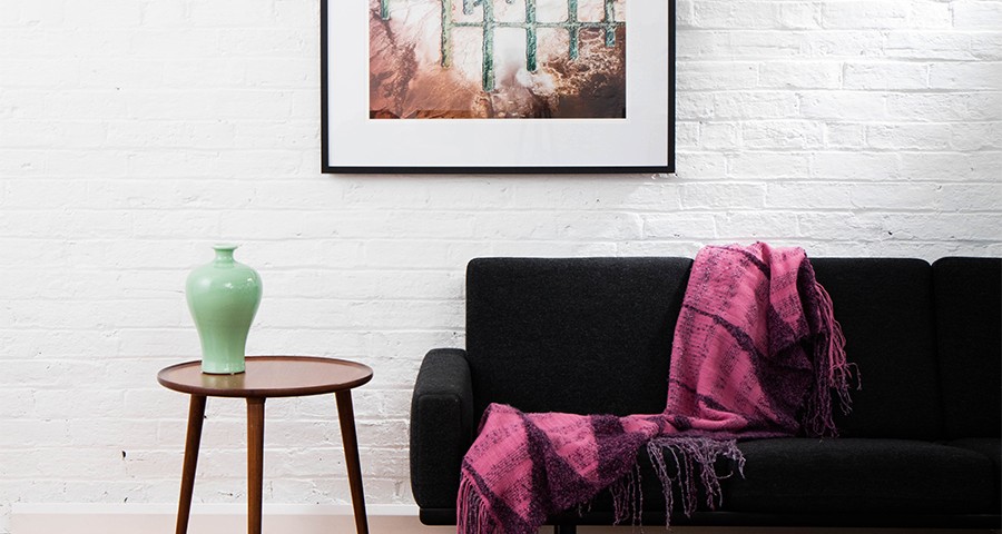 A Vertical Abstract Aerial photo of Australian Landscape in Pink, Purple and Red framed in dark timber in living room