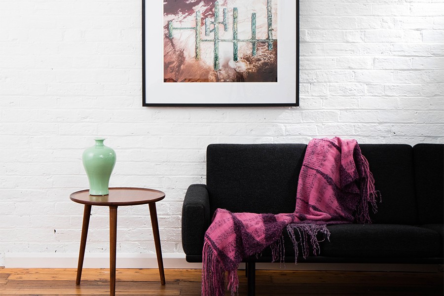 A Vertical Abstract Aerial photo of Australian Landscape in Pink, Purple and Red framed in dark timber in living room