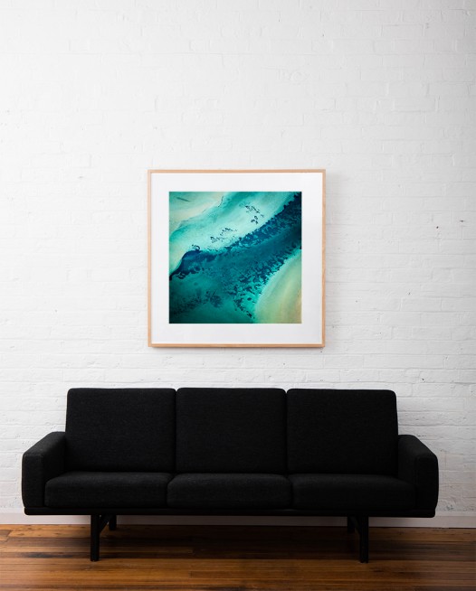 A Square Abstract, Aerial photo of Australia landscape in green and blue framed in raw timber on white wall above sofa