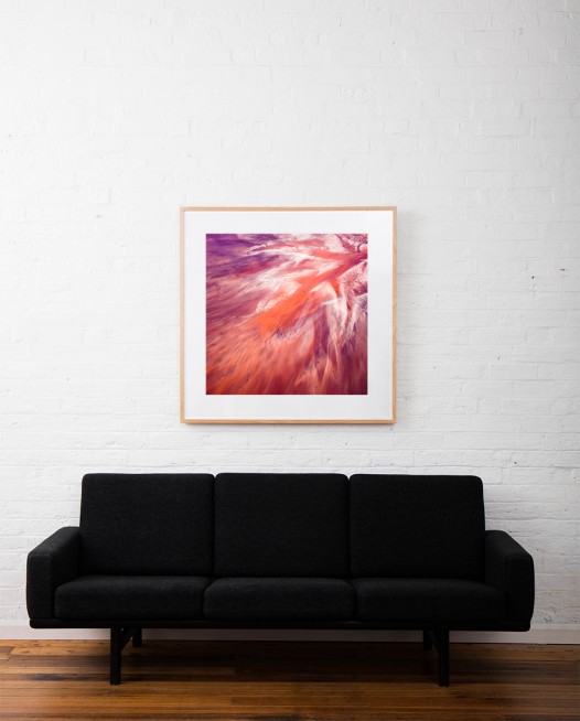 A Large Square Abstract, Aerial photo of Australia Landscape in Pink, Purple and Red framed in raw timber on white wall above sofa