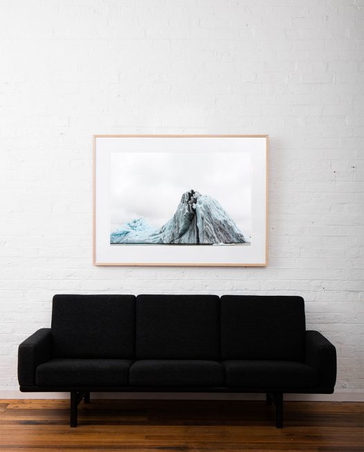 Large Blue and white Icelandic landscape of water, sky, glacier and snow. Framed in raw timber on white wall above sofa