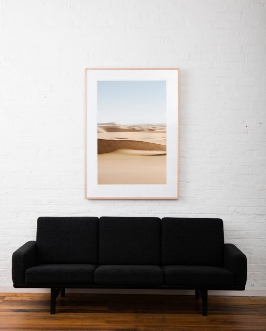 A photograph of Africa desert framed in raw timber on white wall above sofa