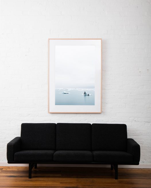 Large Print of Icelandic Landscape of glacier, snow water and sky in blue and white. Framed in raw timber on white wall above sofa