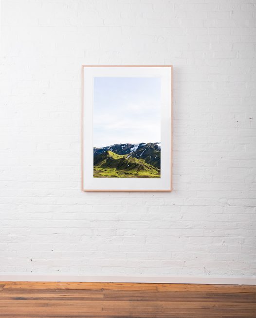 Large Icelandic Landscape photo in green and blue of glaciers, mountain, snow and blue sky.Framed in raw timber on white wall