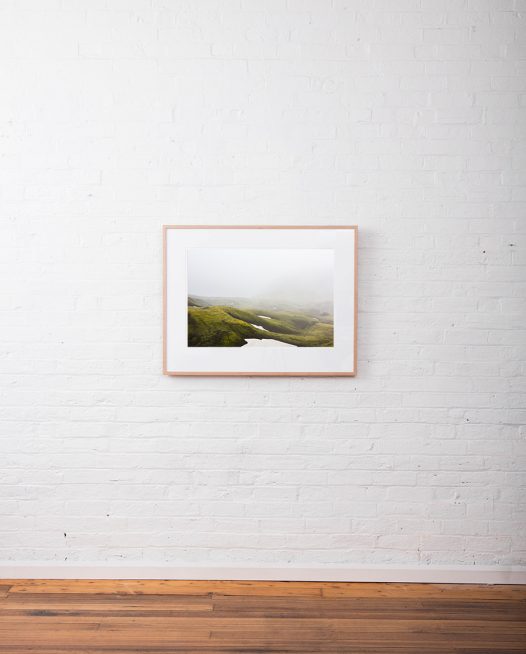 Misty Green Iclandic landscape of mountains and snow framed in raw timber on white wall