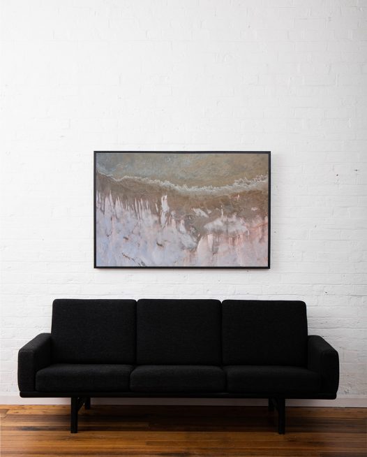 An aerial photo of inland Australia landscape in grey pink and brown color framed in black timber above sofa