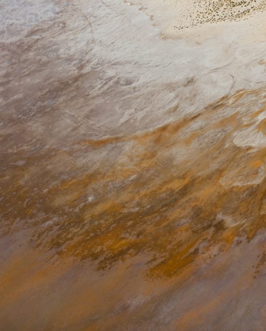 An aerial photo taken of inland Australain landscape in yellow orange pink purple and grey in colour. Image resembles feathered wing